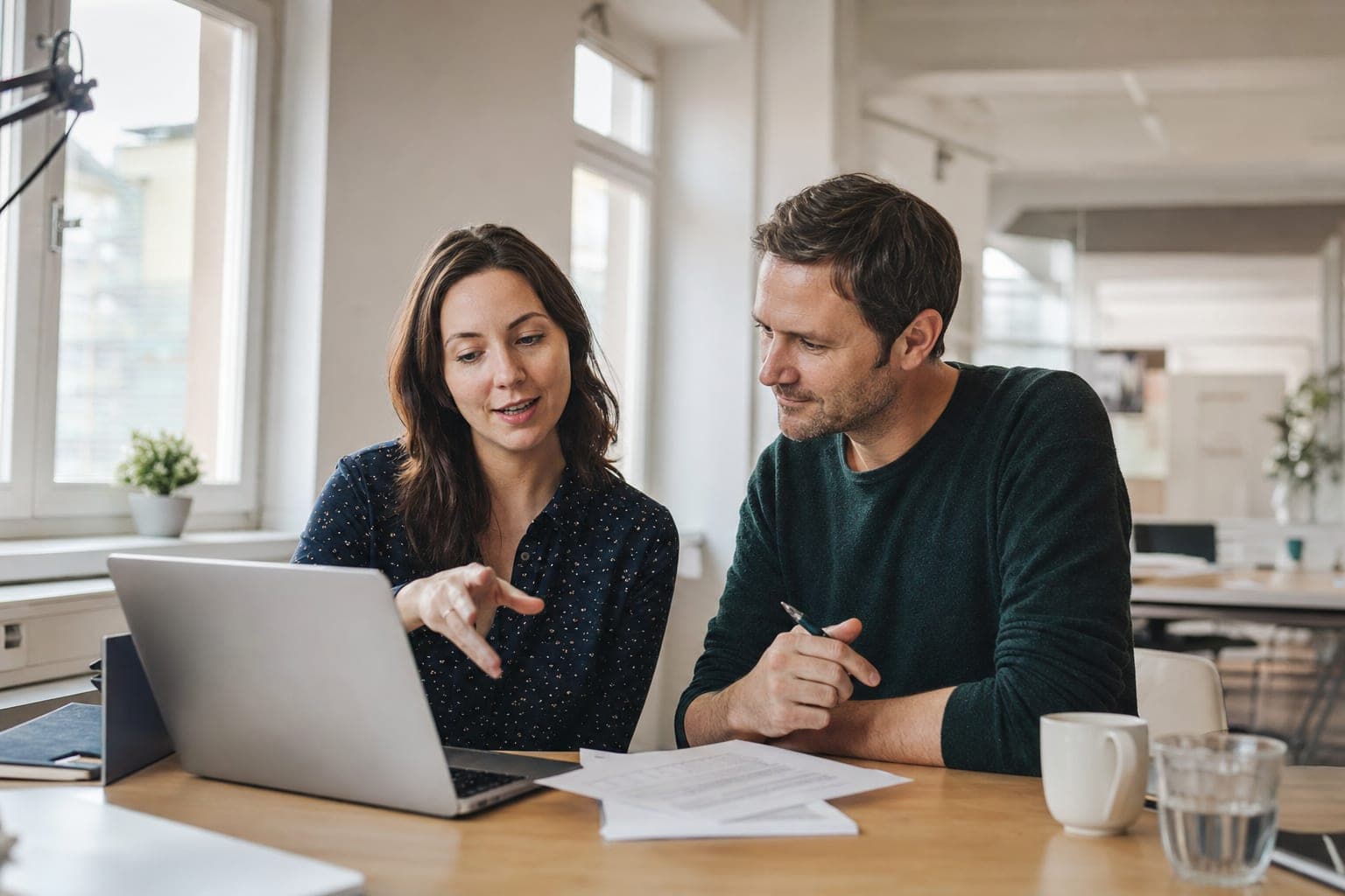Zwei Personen im Büro besprechen am Laptop die offene Stelle